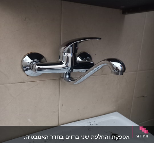ברז קיר מבריק מותקן מעל כיור חרסינה